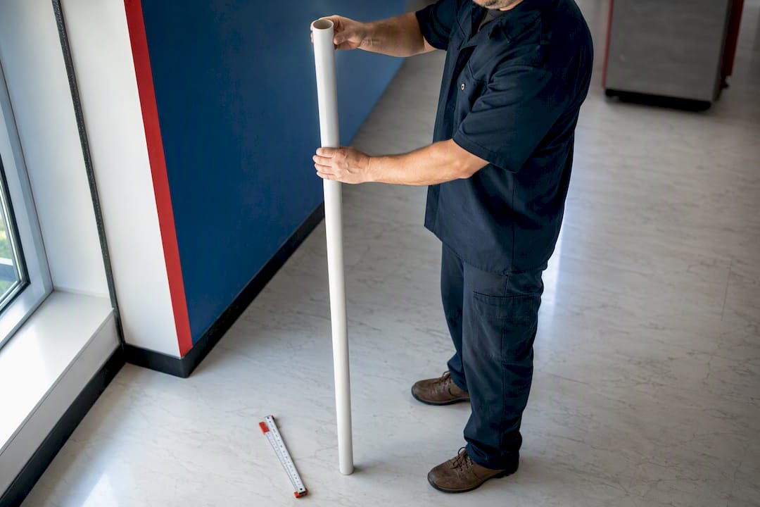 Worker checking reach height with PVC pipe