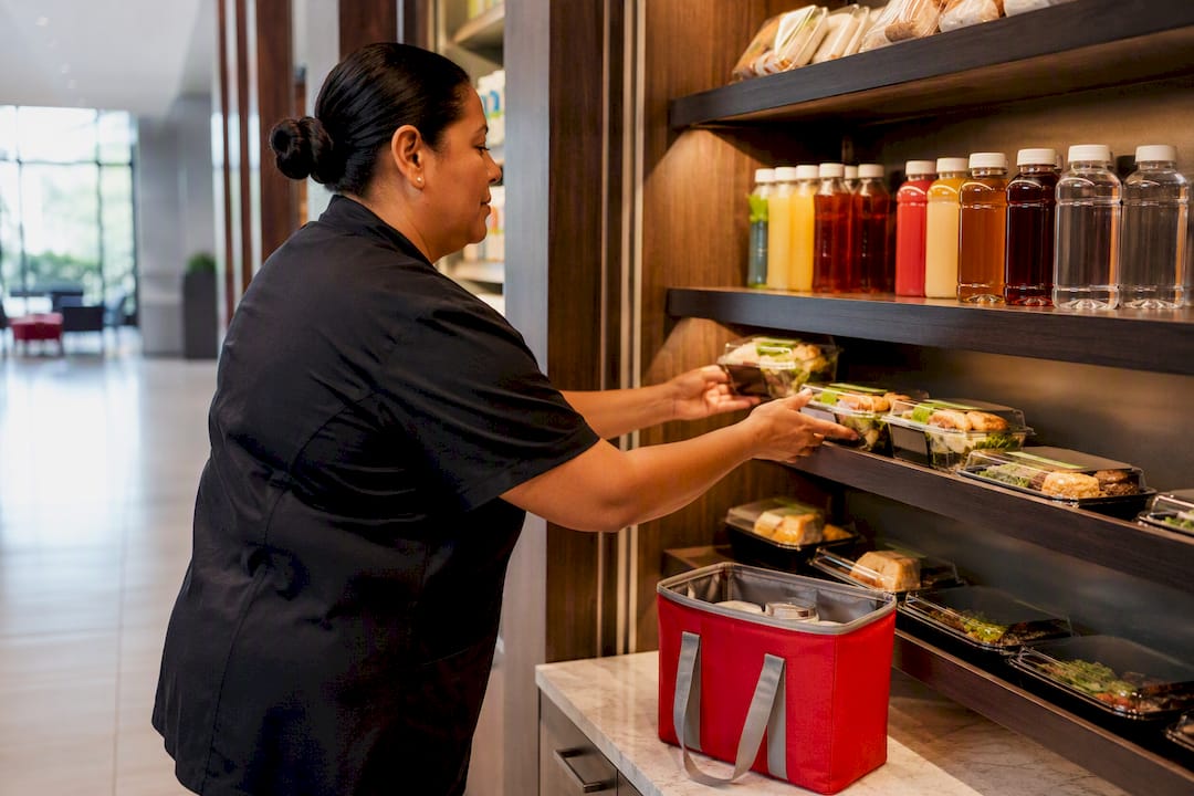 Worker restocking campus refreshment shelf